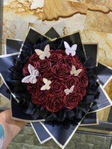 Detail dekat buket bunga mawar handmade dari kain pita satin berkilau dengan paduan warna romantis, dikemas rapi menggunakan kertas wrapping premium.