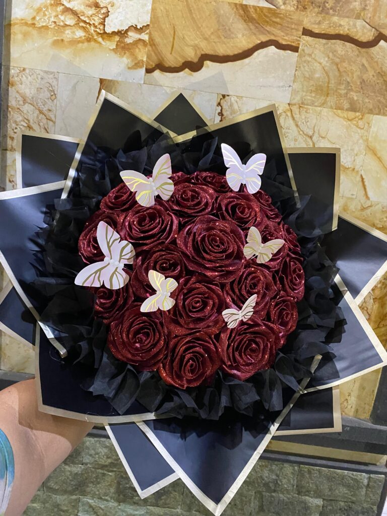 Detail dekat buket bunga mawar handmade dari kain pita satin berkilau dengan paduan warna romantis, dikemas rapi menggunakan kertas wrapping premium.